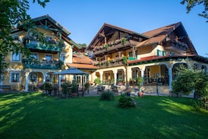 A traditional European-style building with multiple balconies, a covered patio area, and a well-maintained garden. - Landhotel Waldmv Hle (Straß im Attergau)