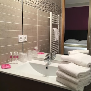 A hotel bathroom with a large sink, mirror, towel rack, and toiletries. - Le Brin D Olivier (Bourg-Saint-Andeol)