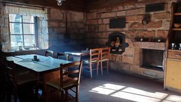A rustic interior with a stone fireplace, wooden furniture, and a window allowing natural light.