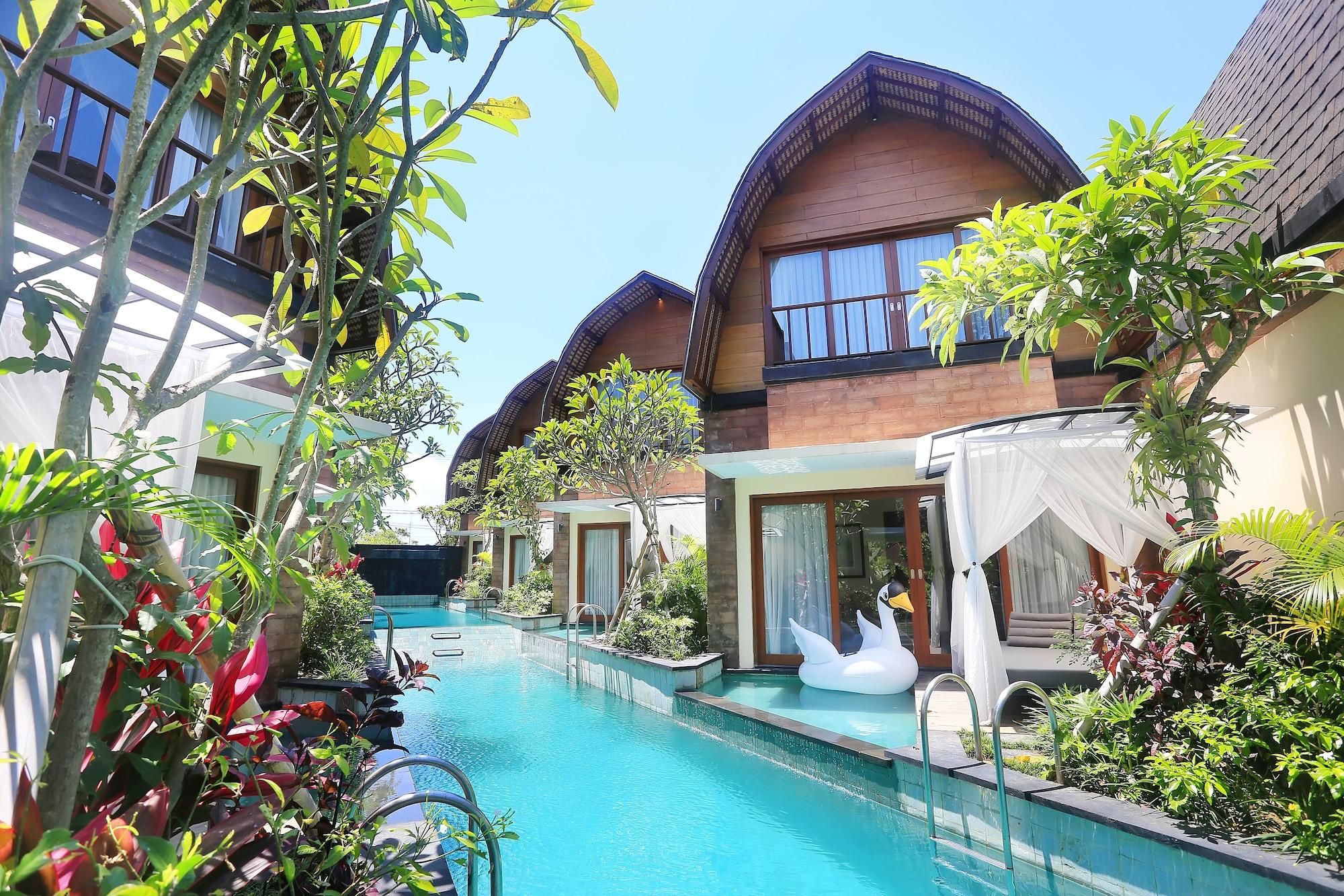 Ein Resort mit Schwimmbad, mehreren Gästezimmern und üppiger Bepflanzung.