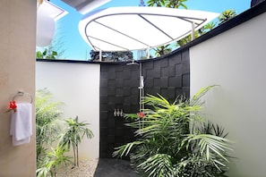 Un bagno moderno con doccia, asciugamano e piante in vaso.