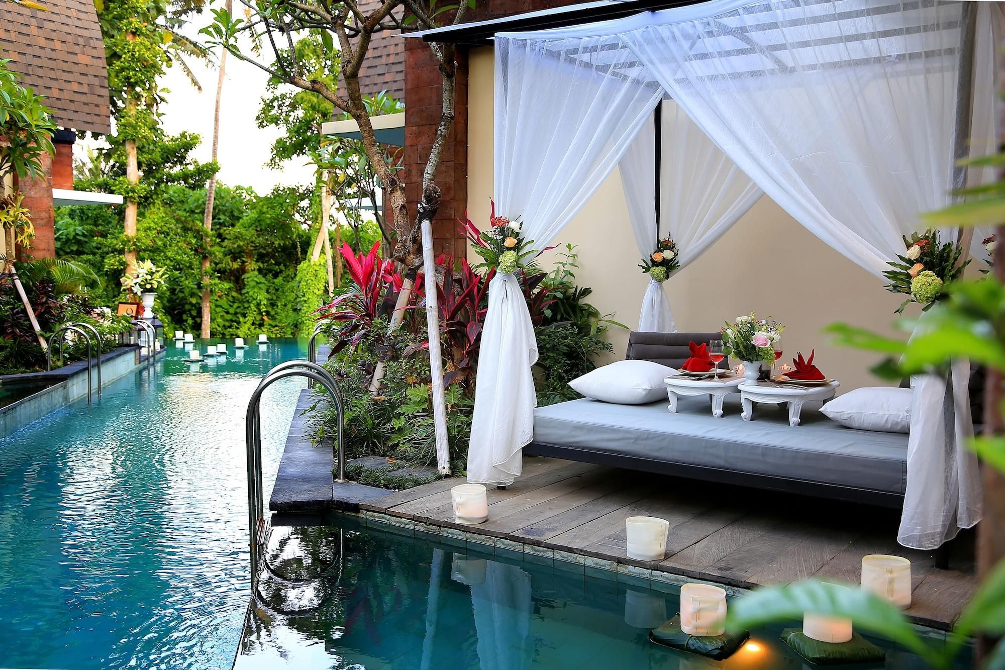 A serene poolside area with a bed, candles, and a view of the pool.