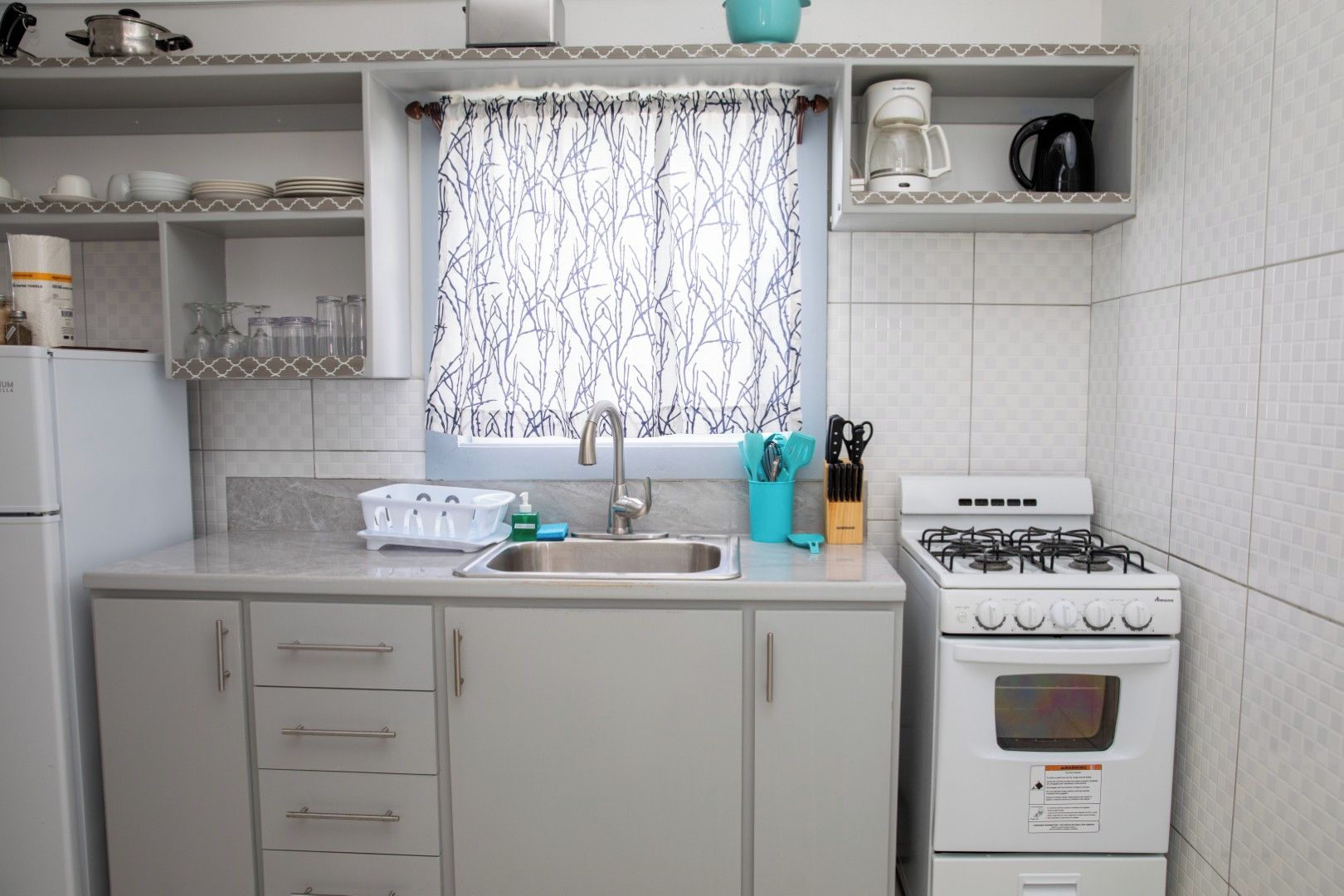Una cocina con pileta, estufa y alacenas.