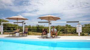 A pool area with lounge chairs, umbrellas, and a sign detailing pool rules. - Neem View Apartments (Falmouth Harbour)