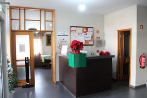 Un área de recepción con un tablón de anuncios, un extintor y un árbol de Navidad.