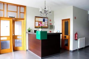 Et receptionsområde med en træreception, en opslagstavle og en brandslukker.