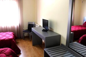 Una habitación de hotel con una cama, un escritorio con una computadora, una silla y un espejo.