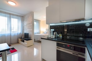 Een moderne keuken met een zwart aanrecht, roestvrijstalen apparatuur en een witte eethoek.