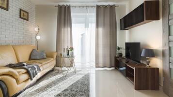 A living room with a sofa, a coffee table, a TV, and curtains.