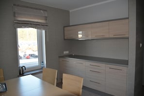 A modern kitchen with a dining table and chairs, a window with blinds, and built-in cabinets.