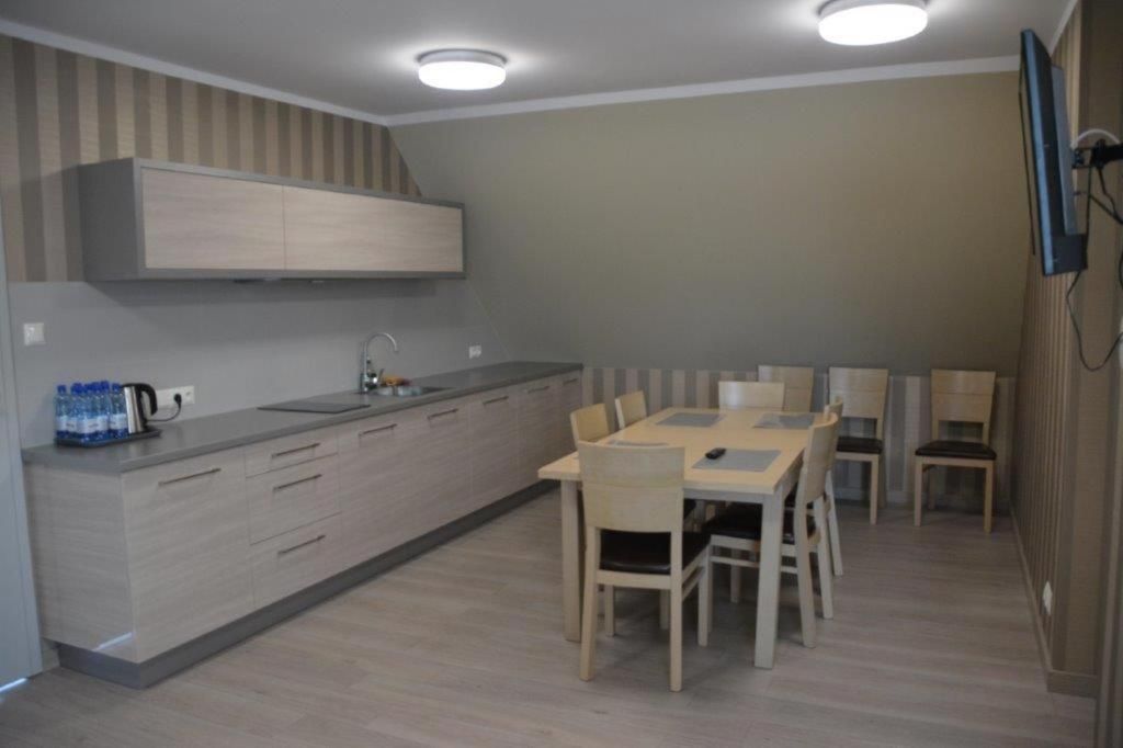 Una cocina moderna con horno integrado, comedor con mesa y sillas, y televisor montado en la pared.