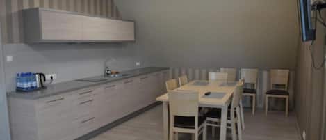 Una cocina moderna con horno integrado, comedor con mesa y sillas, y televisor montado en la pared.