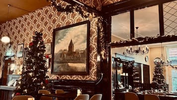 Un restaurant decorat amb calidesa, amb un arbre de Nadal, un quadre emmarcat i una làmpada penjant.