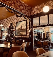 Restaurante decorado com carinho, com árvore de Natal, quadro emoldurado e lustre.