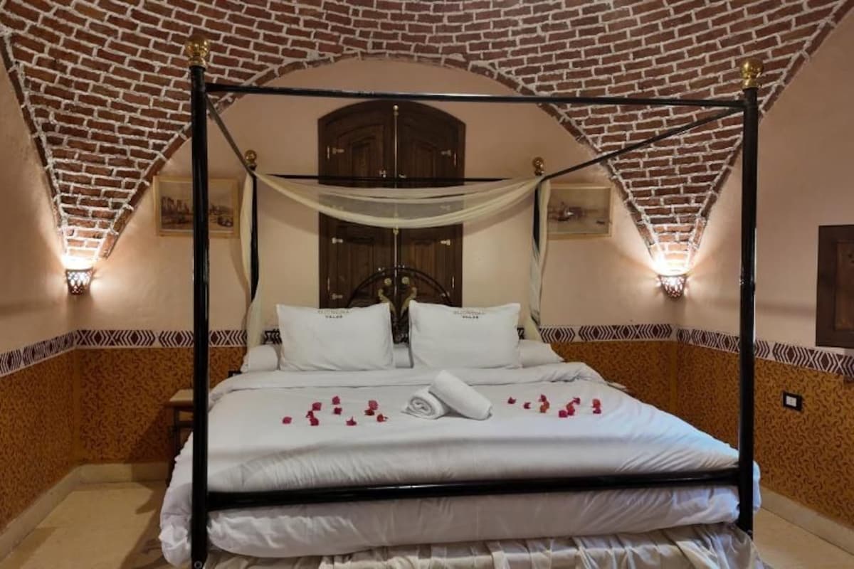 A four-poster bed with a canopy, a wooden door, and patterned walls.