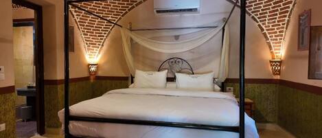 A four-poster bed with a canopy, a wall-mounted air conditioner, and two wall sconces.