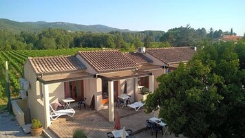 Un edificio con techo de tejas, zona de estar al aire libre y vistas a un viñedo.