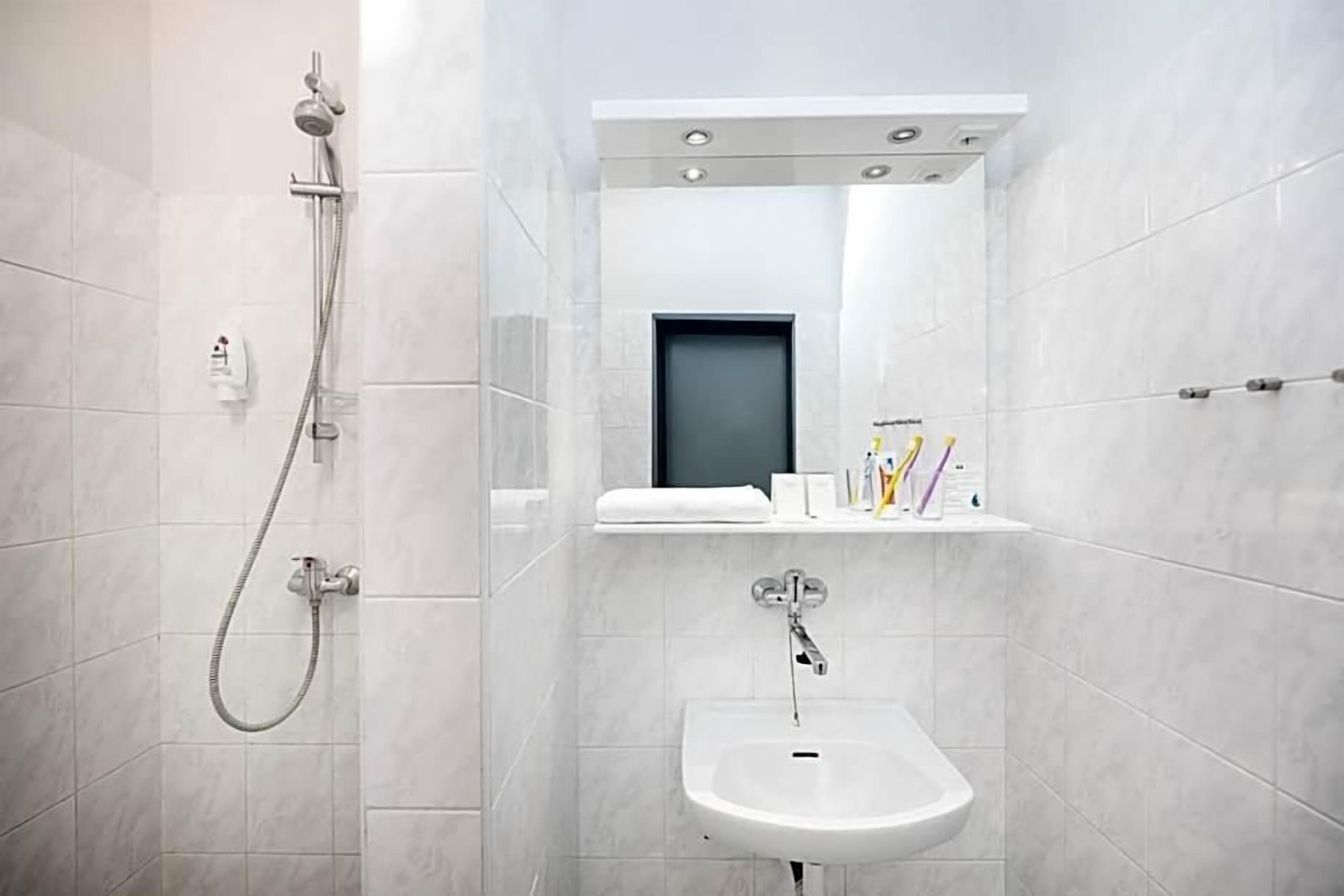 Un baño con ducha, lavamanos y espejo.