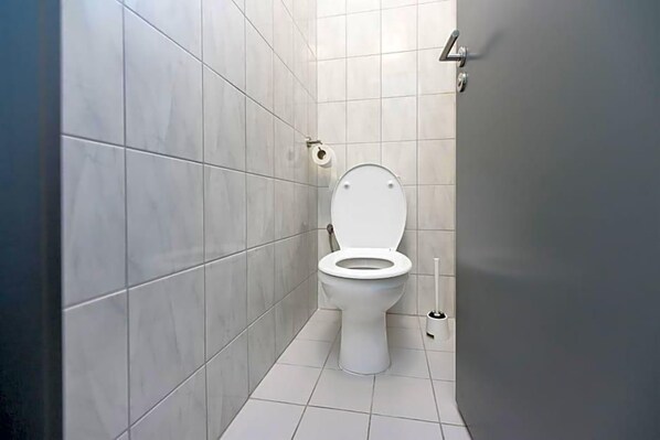 A bathroom with a toilet, a toilet paper holder, and a bidet.