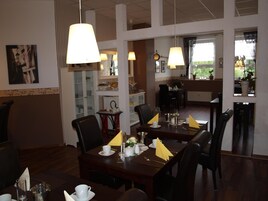 A dining area with tables set for service, chairs, and hanging lamps.