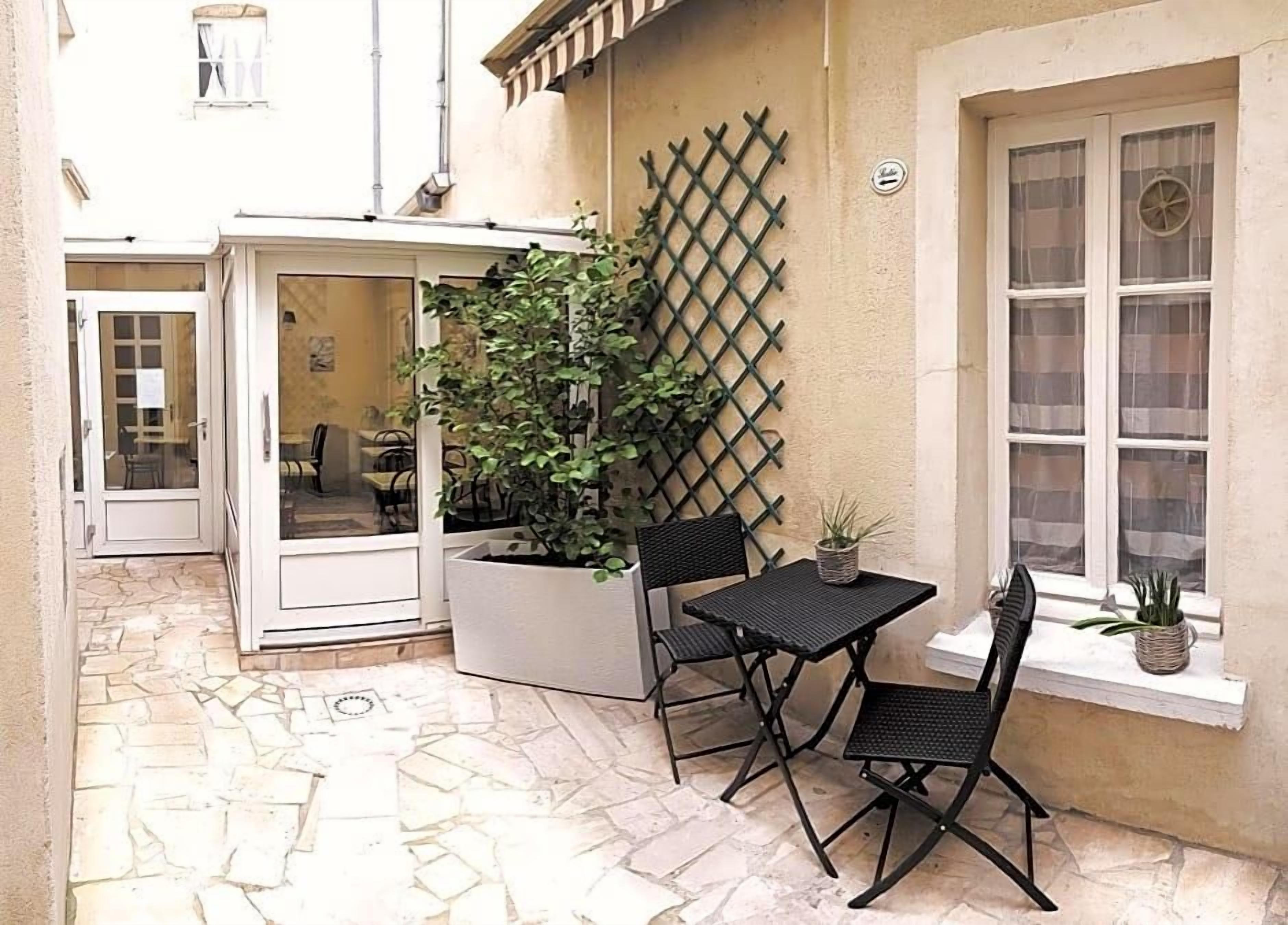 An outdoor patio with a table and chairs, a potted plant, and a lattice wall.