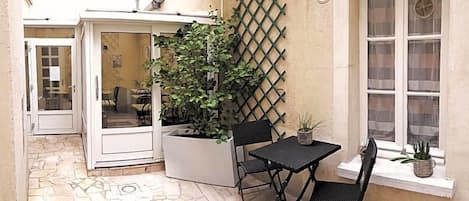 An outdoor patio with a table and chairs, a potted plant, and a lattice wall.