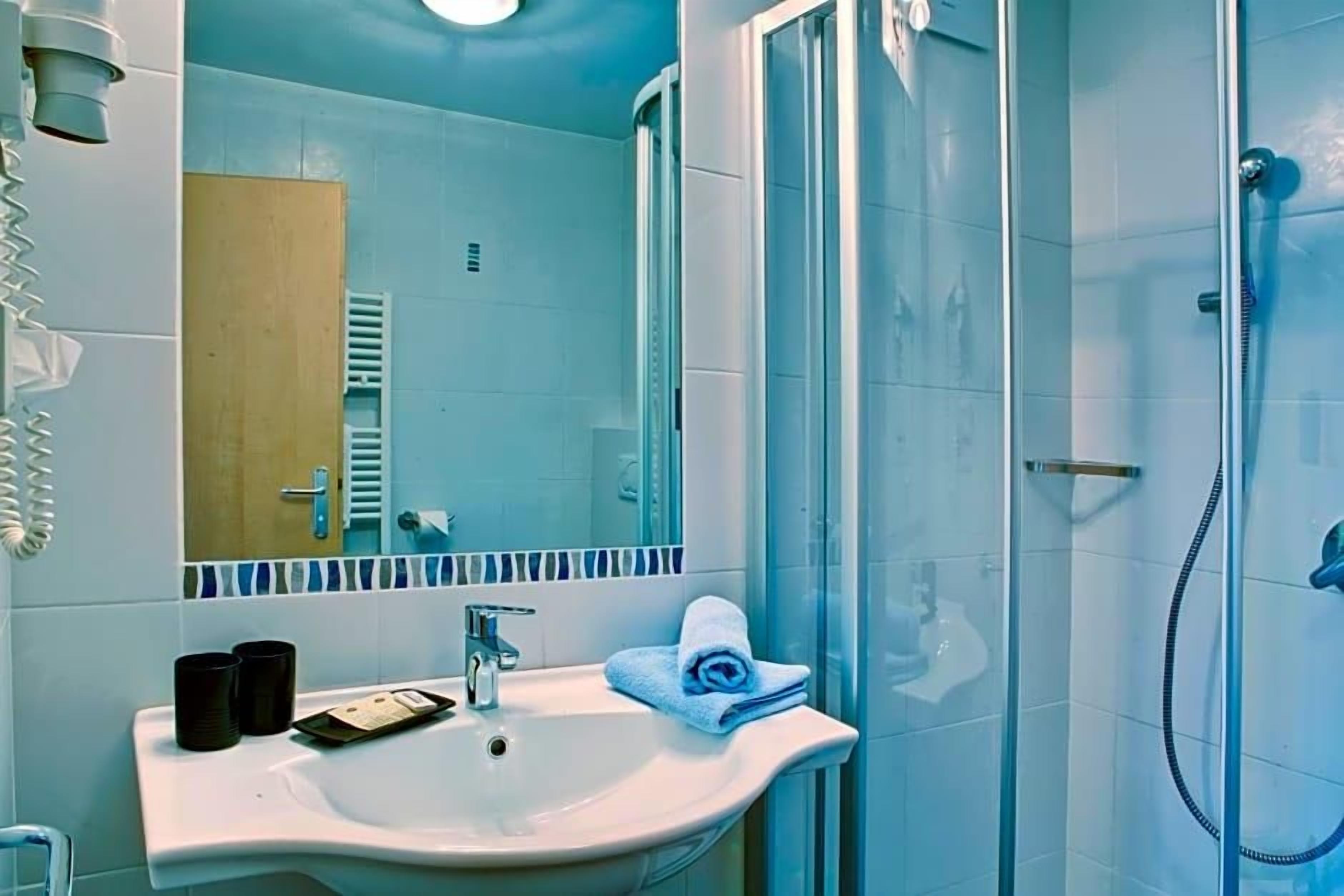 A bathroom with a sink, mirror, and shower.