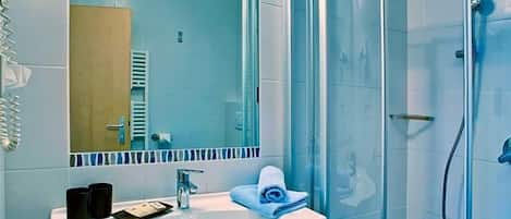 A bathroom with a sink, mirror, and shower.
