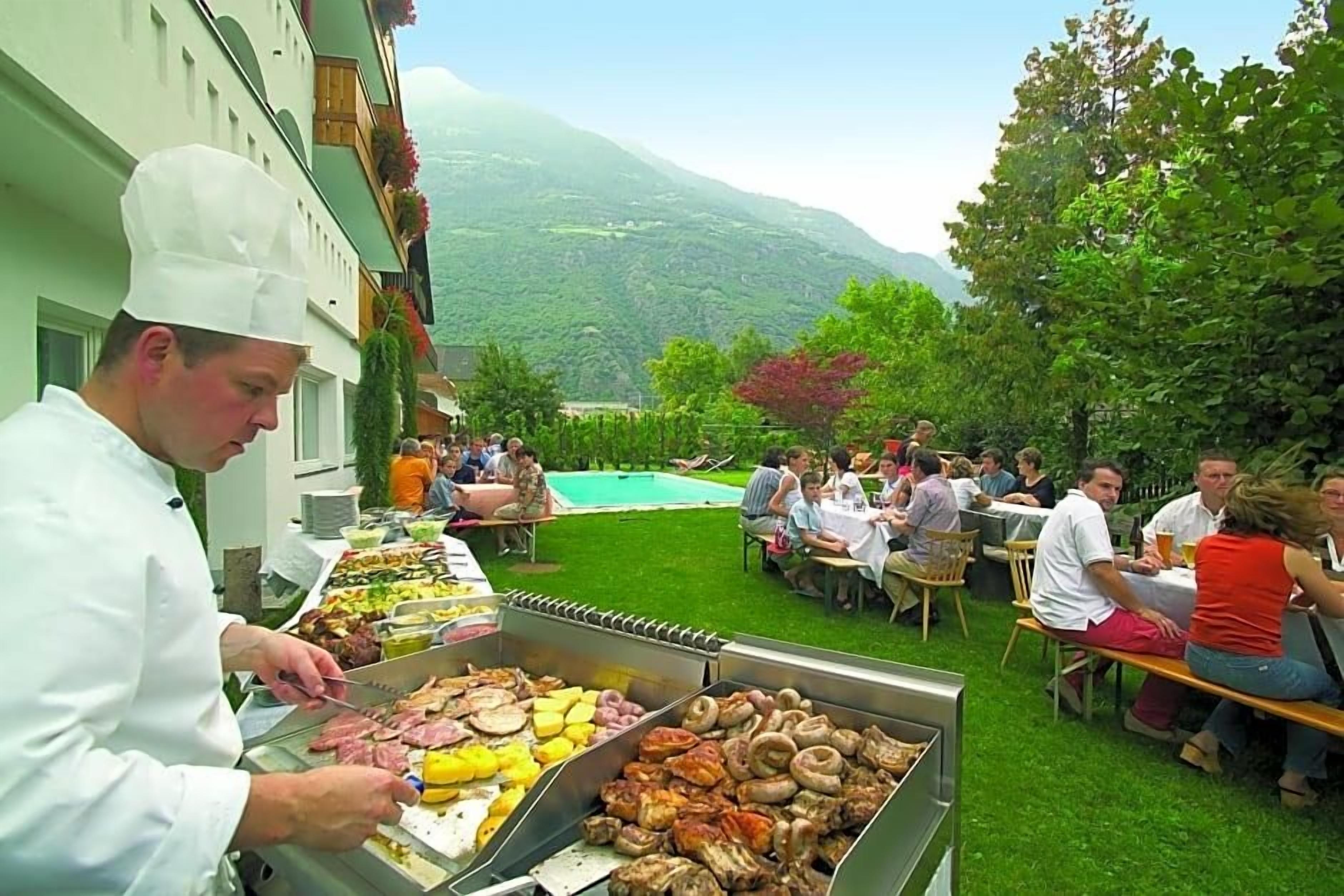 An outdoor dining area with a chef preparing food, surrounded by guests.