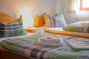 Ein Hotelzimmer mit zwei Betten, jeweils mit einer grün-blauen Streifenauflage, einem weißen Handtuch und einem Nachttisch mit Lampe und Flasche.