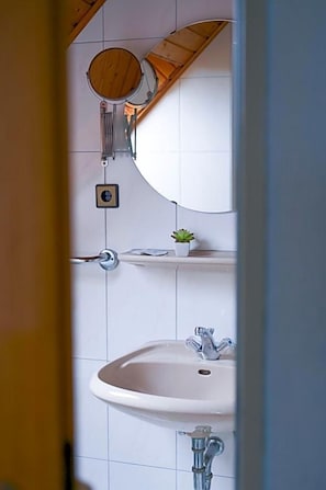 Ein Badezimmer mit Toilette, Waschbecken, Spiegel und einer kleinen Topfpflanze.