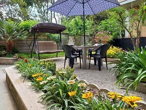 An outdoor seating area with a table and chairs, surrounded by a garden with various plants and flowers. - Hotel Cormorano (Pedaso)