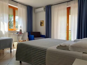 A hotel room with a bed, a desk, a chair, and a view of the outdoors. - Hotel Cormorano (Pedaso)