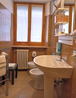 A bathroom with a toilet, sink, and window. - Hotel Cormorano (Pedaso)