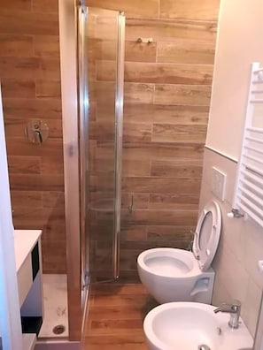A bathroom with a glass shower enclosure, a toilet, and a sink. - Locanda La Gozzetta (Santa Luce)