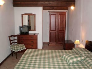 A room with a bed, a dresser, a television, a mirror, and a wardrobe.