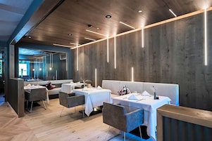 A modern restaurant interior with wooden walls, tables, and chairs.