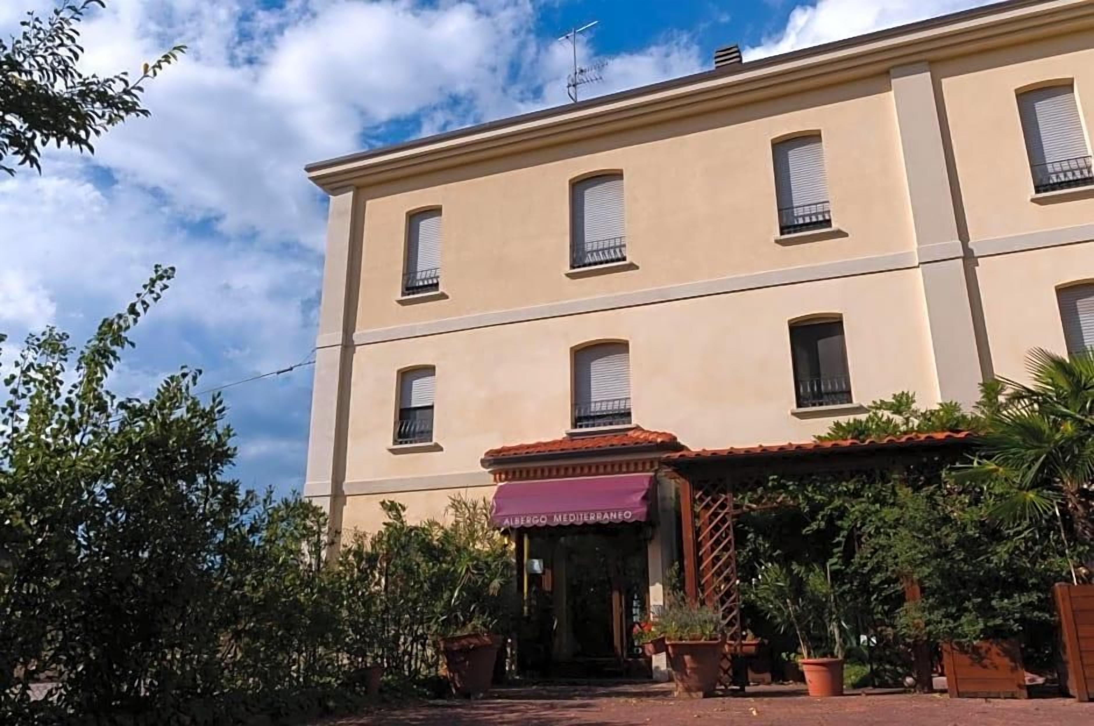 A two-story building with a sign reading 'Albergo Mediterraneo' at the entrance.