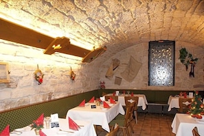 Un espace de restauration intérieur avec des murs en pierre, des poutres en bois et des tables dressées pour le repas.