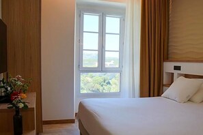 A hotel room with a bed, a window with curtains, a wooden headboard, and a vase with flowers. - Le Royal Hv Tel Restaurant (Bonifacio)
