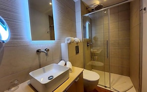 A modern bathroom with a glass-enclosed shower, a white sink, and a toilet. - Le Royal Hv Tel Restaurant (Bonifacio)