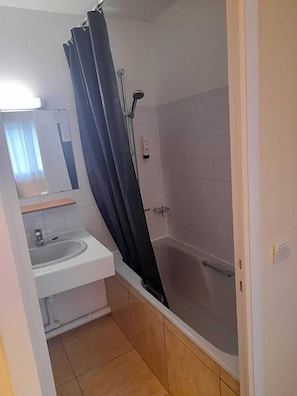 Un baño con ducha, lavamanos y espejo.