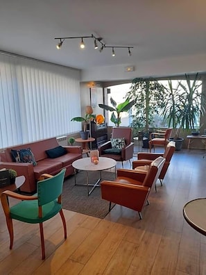 Una sala de estar moderna con un sofá, sillas, una mesa de centro y plantas en macetas.