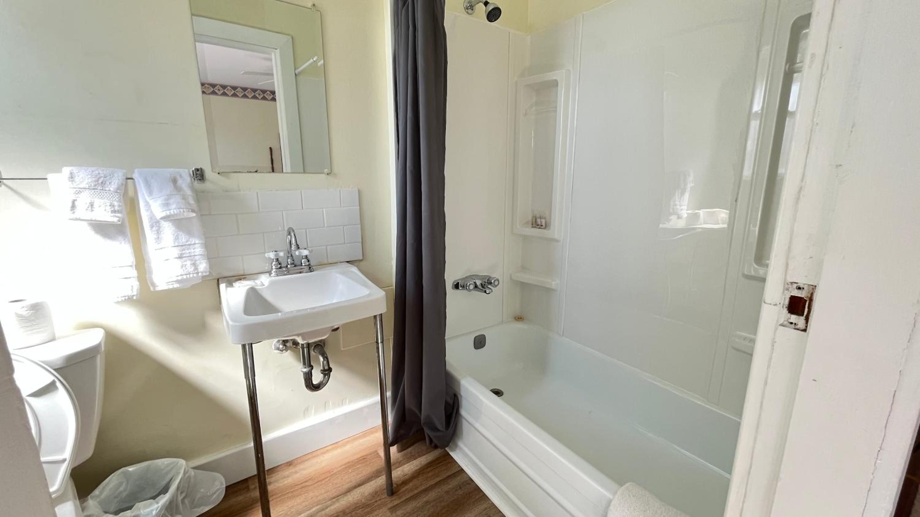 A bathroom with a white sink, mirror, and bathtub.