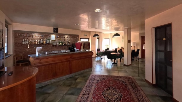 Un vestíbulo de hotel con zona de bar, comedor y alfombra estampada.