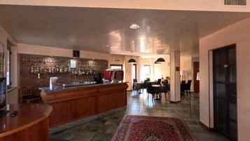 Eine Hotelhalle mit Barbereich, Essbereich und einem gemusterten Teppich.