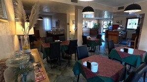 Un restaurante con mesas cubiertas con manteles verdes, sillas negras e iluminación colgante.