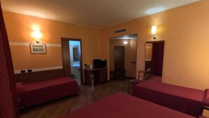 Habitación de hotel con dos camas, un escritorio, un televisor y la puerta del baño.