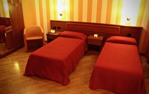 Een hotelkamer met twee éénpersoonsbedden, een stoel, een nachtkastje en een spiegel.
