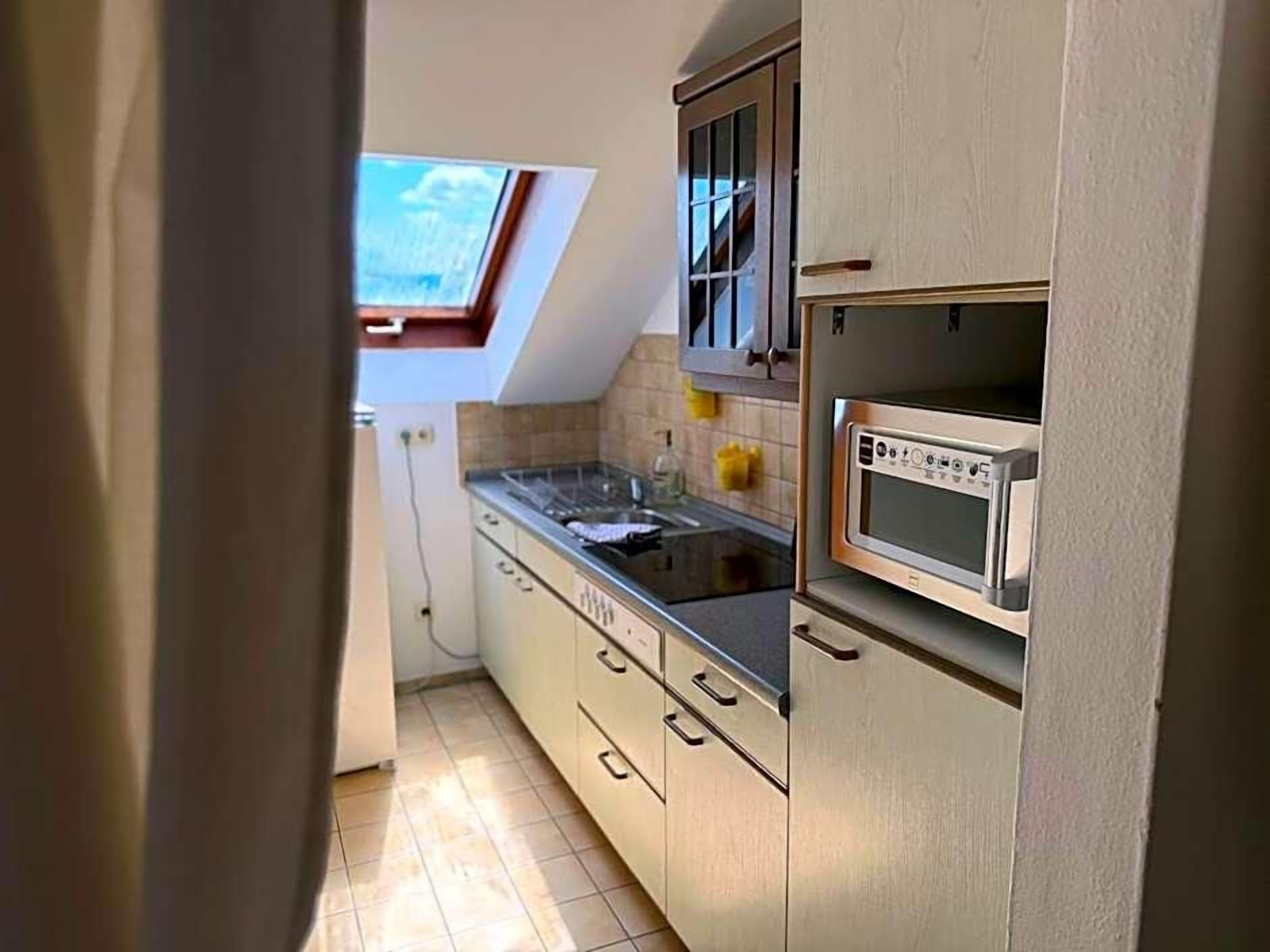 Une cuisine équipée d’un four encastré, d’un four à micro-ondes et d’une fenêtre située au-dessus de l’évier.